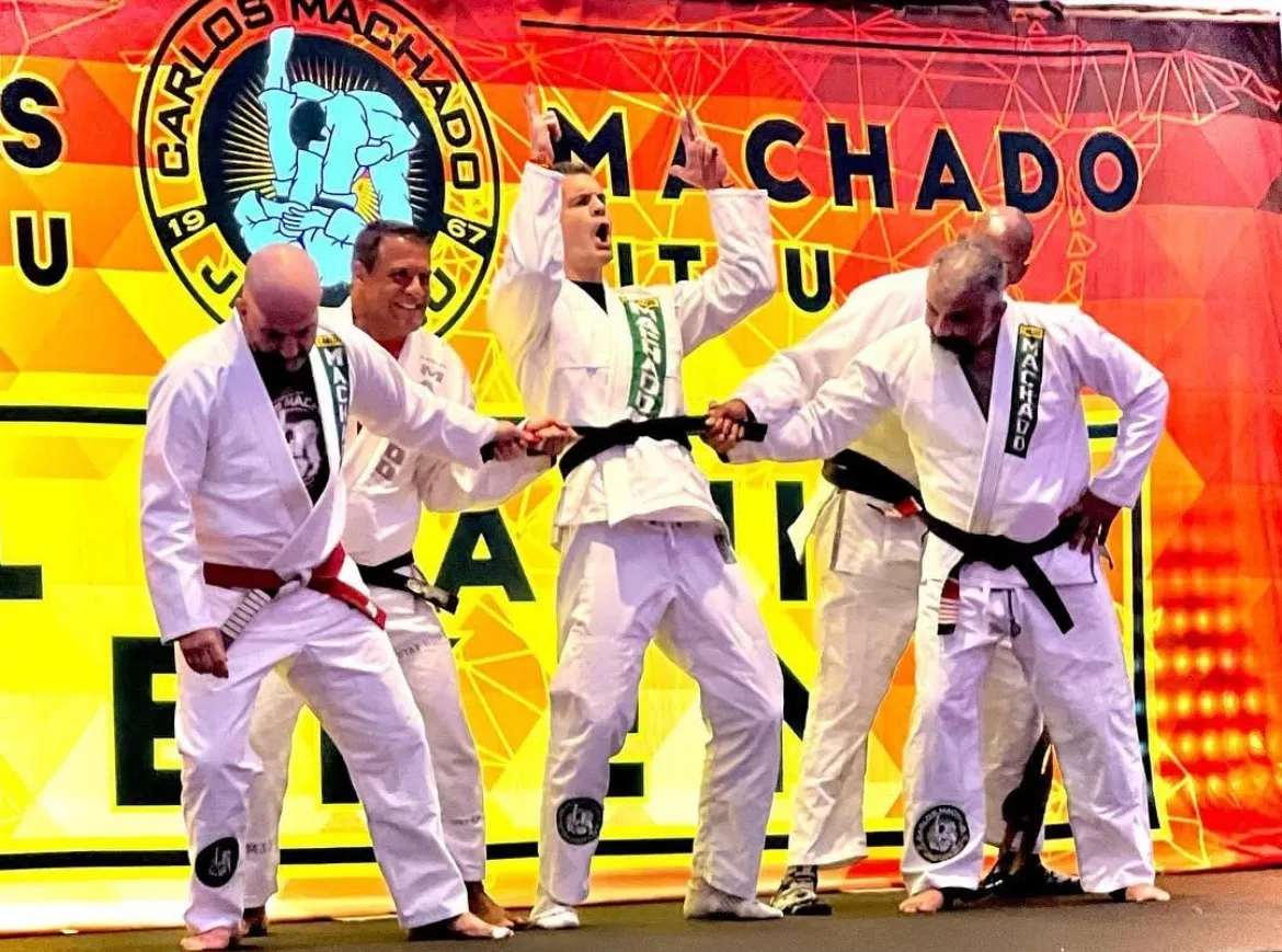 Machado black belts tying a new black belt on a student at a Carlos Machado Jiu-Jitsu promotion ceremony