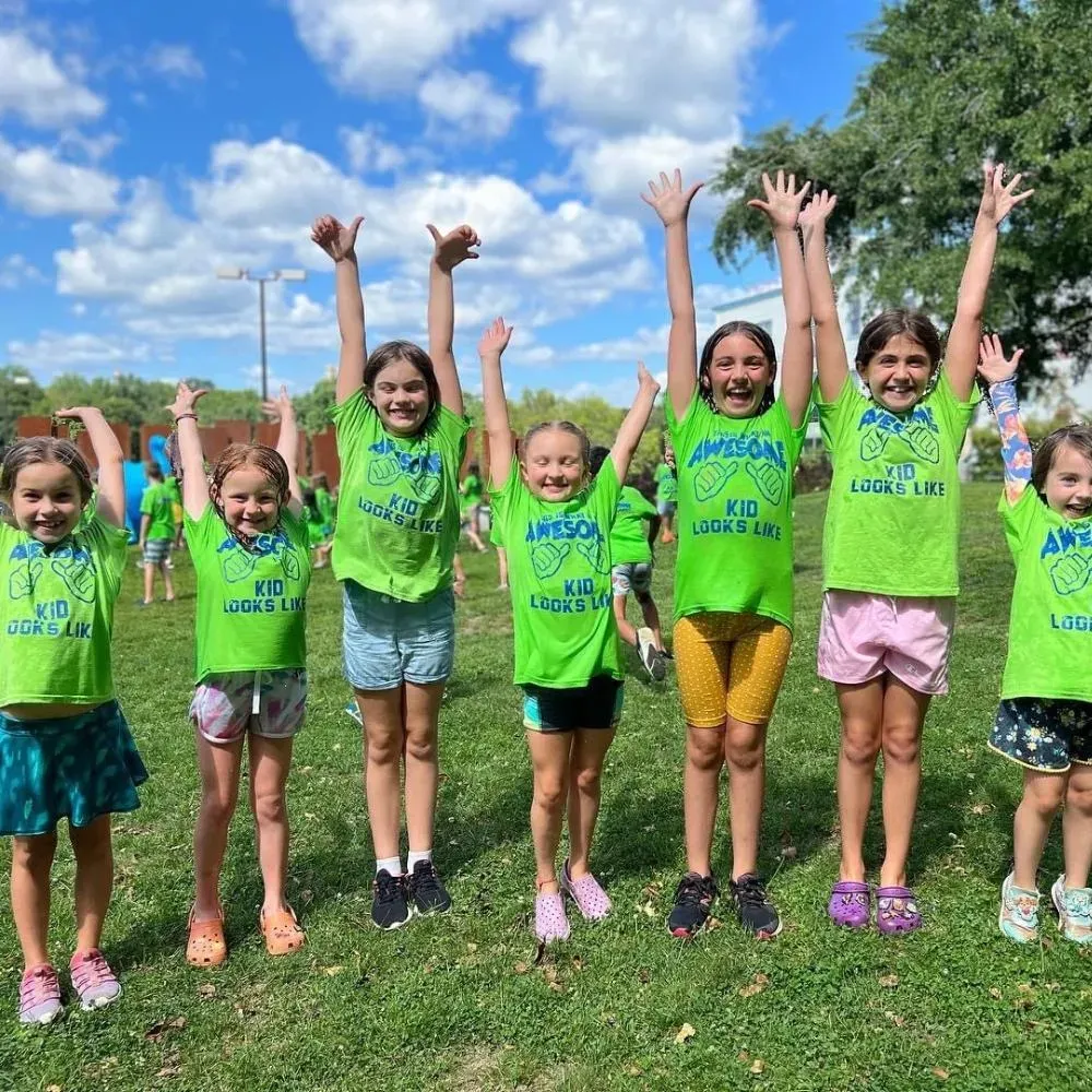Machado Method summer campers cheering outdoors with their arms raised in Carrollton, TX