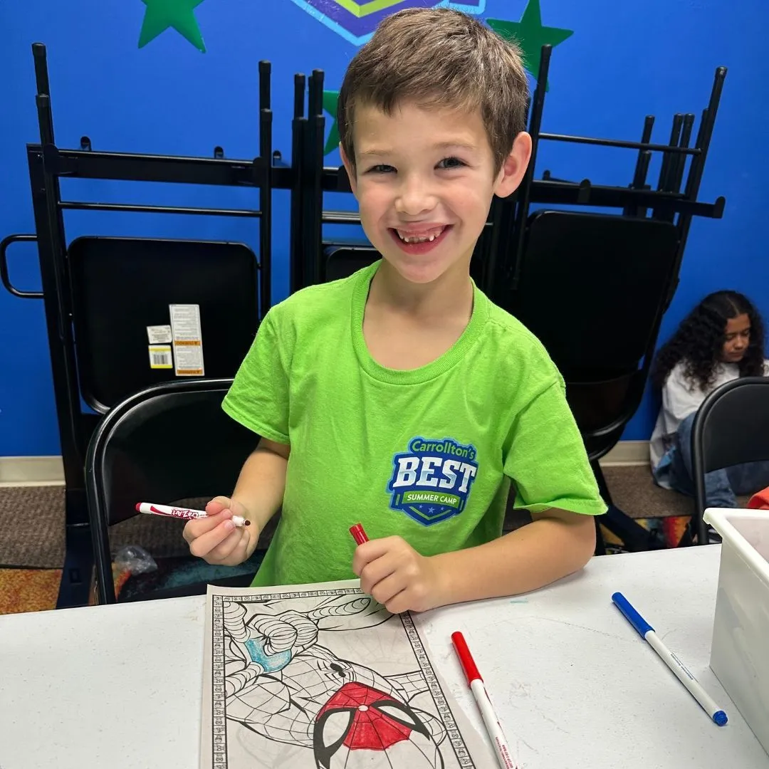 A young Machado Method summer camper smiling while coloring in Carrollton, TX